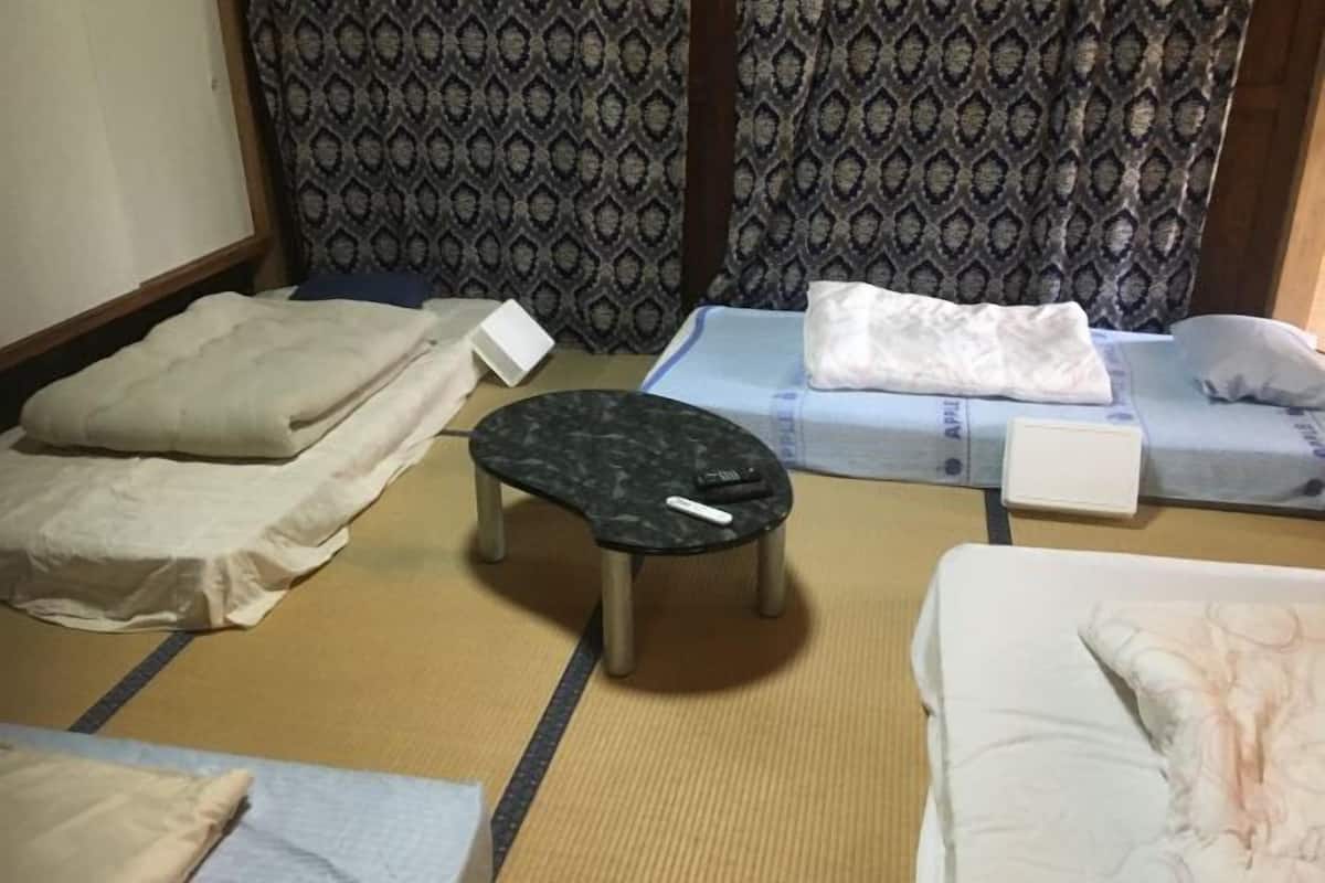 Ein Hotelzimmer mit zwei Betten, einem kleinen Tisch und einem gemusterten Vorhang.