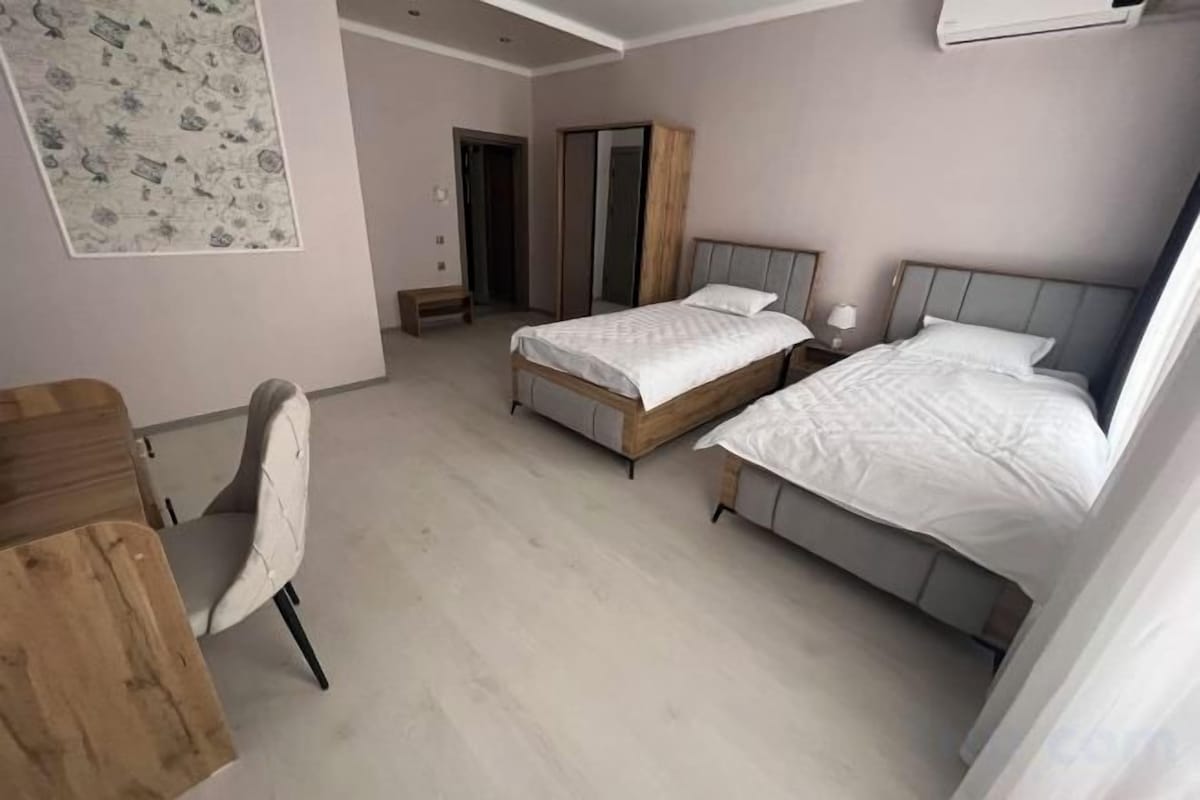 A bedroom with two beds, a desk, and a chair.