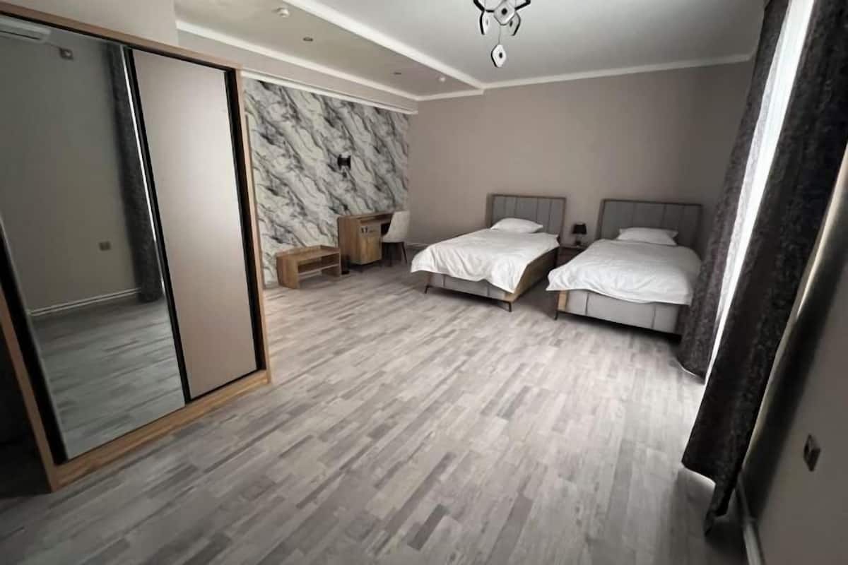 Een slaapkamer met twee bedden, een kledingkast, een marmeren wand en een houten vloer.