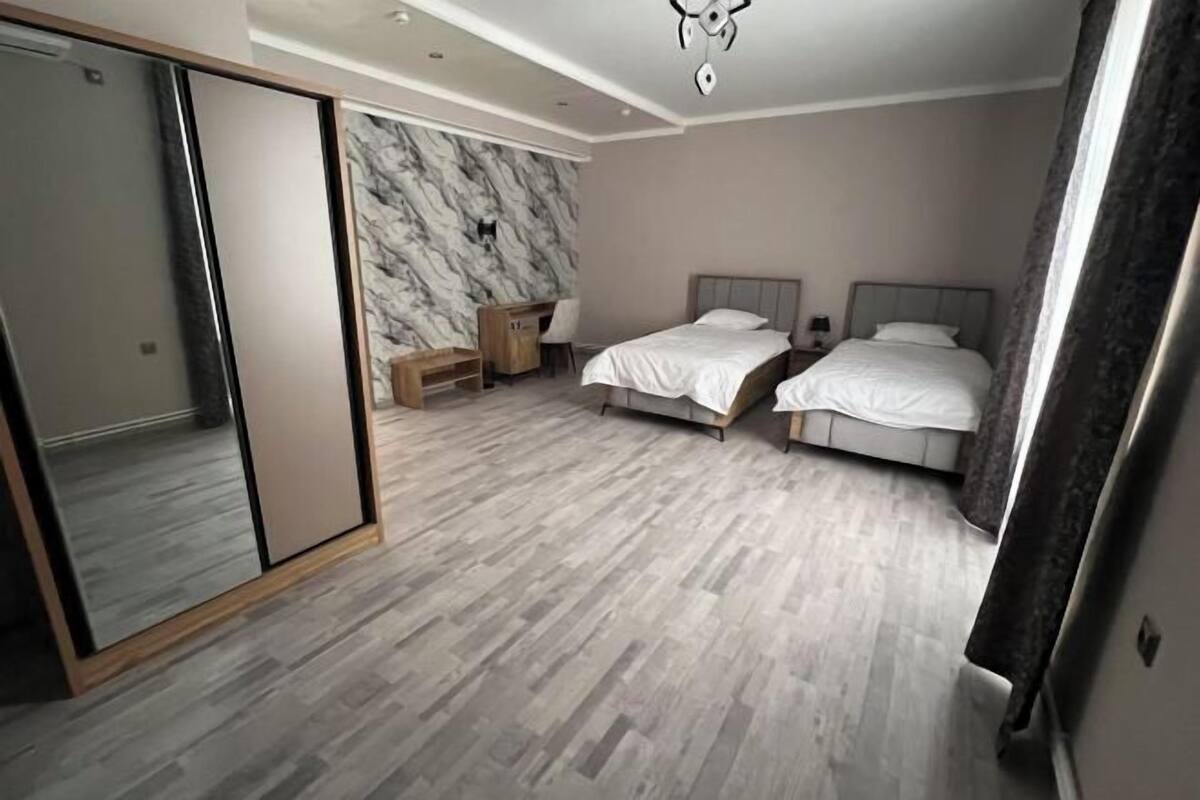A bedroom with two beds, a wardrobe, a marble wall, and a wooden floor.
