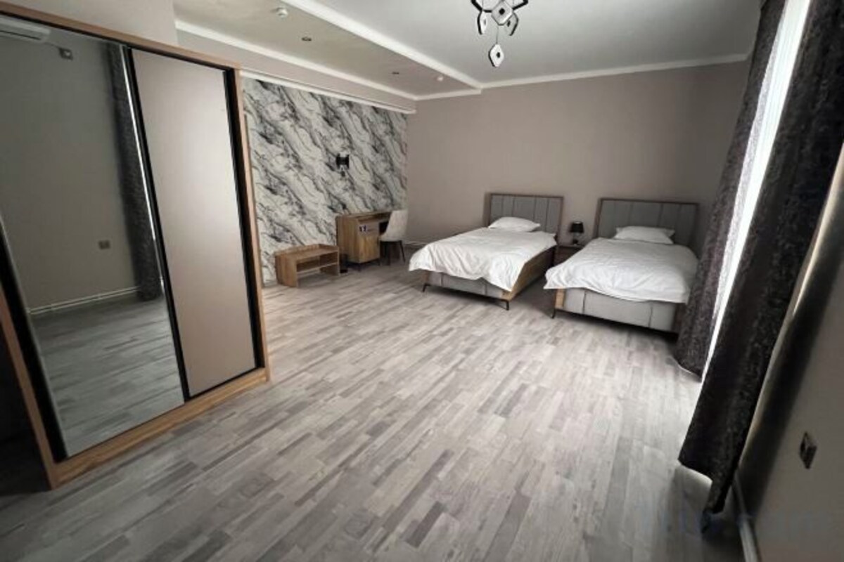 Une chambre avec deux lits, un miroir, une armoire et un mur en marbre.