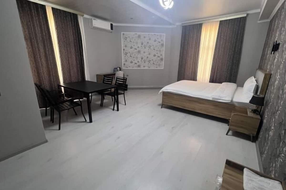 Een compacte hotelkamer met een bed, een klein bureau en een stoel.