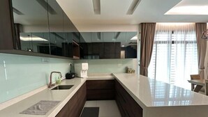Een moderne keuken met een groot eiland, donkerhouten kasten en een glazen spatwand.