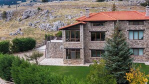 Una casa in pietra con tetto in tegole rosse, ampie finestre e una scala in pietra che conduce all'ingresso.