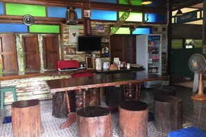 Un espace bar avec un long comptoir, des tabourets et un téléviseur.