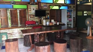 Un coin bar rustique avec des tabourets en bois, un comptoir et un réfrigérateur rempli de boissons.