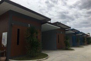 Une rangée de chambres d’hôtel modernes, dotées d’un espace extérieur couvert et d’un parking.