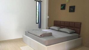 Une chambre à coucher avec un lit, une fenêtre avec des rideaux et un mur orné de deux tableaux encadrés.