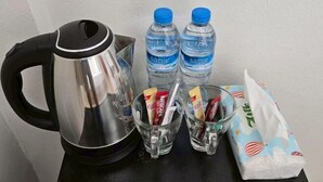 A kettle, two water bottles, two glasses with coffee packets, and a tissue box on a table. - The White Residence (Chanthaburi)