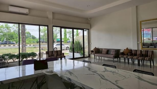 A spacious lobby with a marble reception desk, comfortable seating, large windows, and a view of the outdoors. - The White Residence (Chanthaburi)