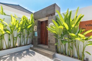 A building entrance with a door, a small porch, and a sign. - Villa Lange 2 (Bali)