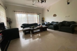 A living room with a sofa set, a coffee table, and a television. - Costco Chinese Hotel (Islamabad)