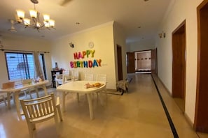 A dining area with a table and chairs, a chandelier, and a 'Happy Birthday' decoration on the wall. - Costco Chinese Hotel (Islamabad)