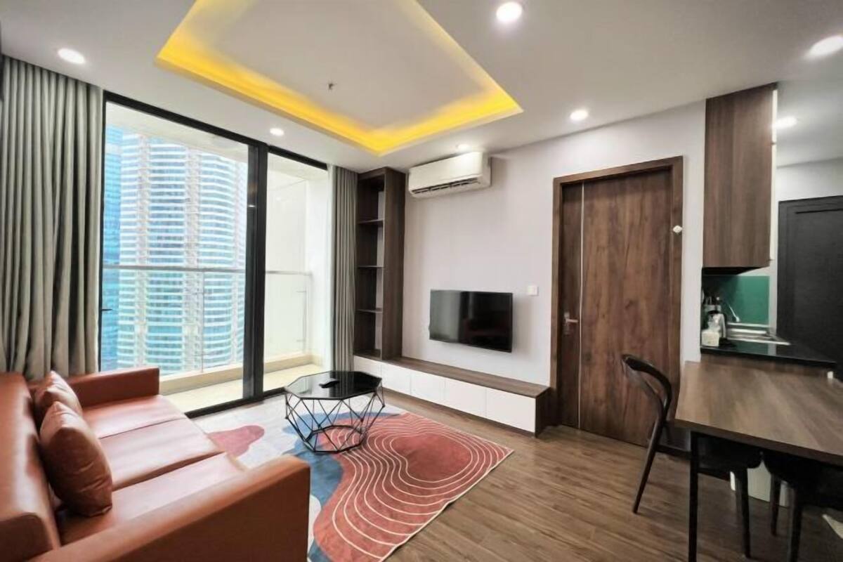 Uma sala de estar moderna com um sofá, uma mesa de jantar e uma TV fixada na parede.