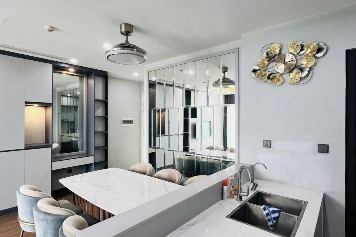 Cozinha moderna com ilha de mármore, banquetas e um relógio decorativo na parede.