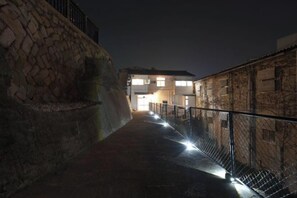 A pathway leading to a building with a stone wall on one side and a metal fence on the other, under nighttime lighting. - Injie Hotel Shimonoseki (Shimonoseki)