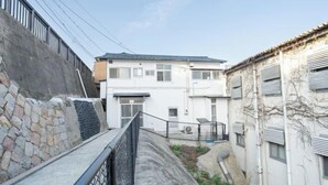 A narrow alleyway between buildings with a stone wall on one side and a white building with a black roof on the other. - Injie Hotel Shimonoseki (Shimonoseki)