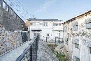 A narrow alleyway with a building on the right, a stone wall on the left, and a metal railing in the foreground. - Injie Hotel Shimonoseki (Shimonoseki)