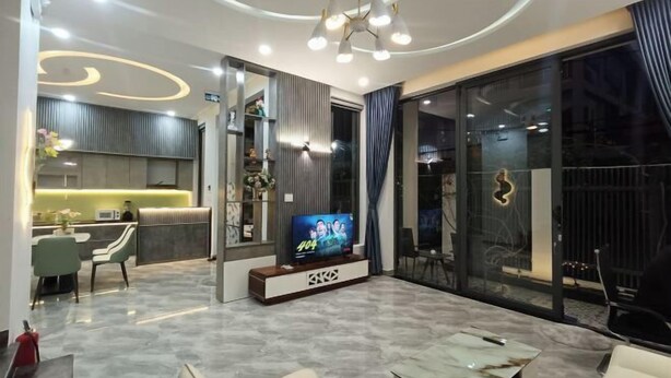 A modern living room with a TV, seating, and a kitchen area. - Aroma Beach (Da Nang)