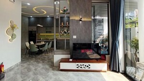A modern living room with a fireplace, a dining area, and a kitchen in the background. - Aroma Beach (Da Nang)