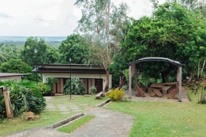 A garden with a pathway leading to a building, surrounded by greenery and a view of the landscape. - Spacio Caliraya Events Venue and Resorts (Lumban)