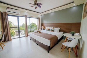 A hotel room with a bed, a desk, and a chair. There is a balcony with a view of the outdoors. - Spacio Caliraya Events Venue and Resorts (Lumban)