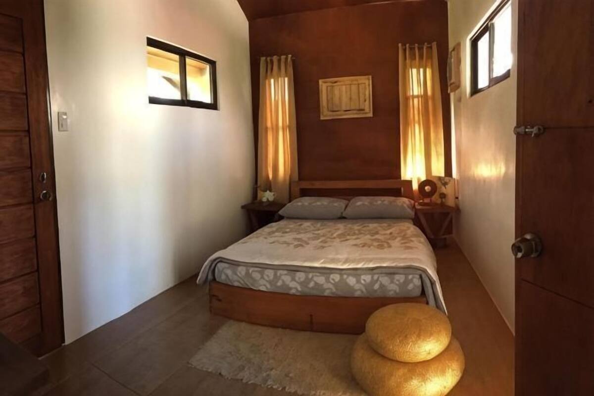 Une chambre à coucher avec un lit, des tables de chevet, une armoire en bois et une petite table ronde.
