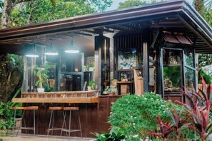 A rustic outdoor bar with a wooden counter and stools, surrounded by greenery. - Spacio Caliraya Events Venue and Resorts (Lumban)