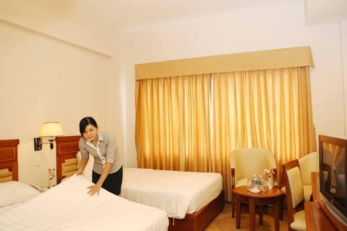 A hotel room with two beds, a TV, a chair, and a table.