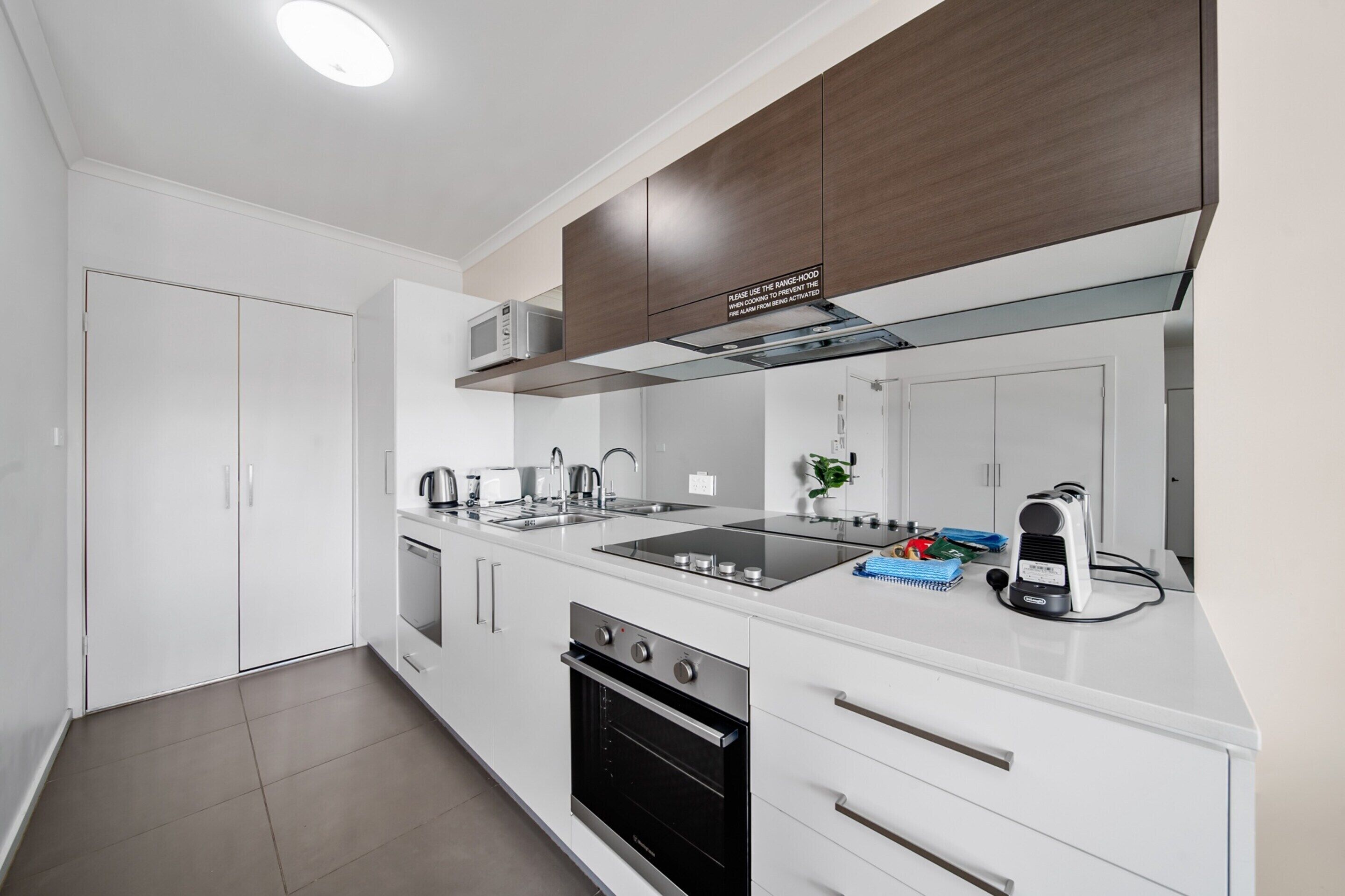 Cocina moderna con armarios blancos, estufa de acero inoxidable, horno empotrado y microondas.