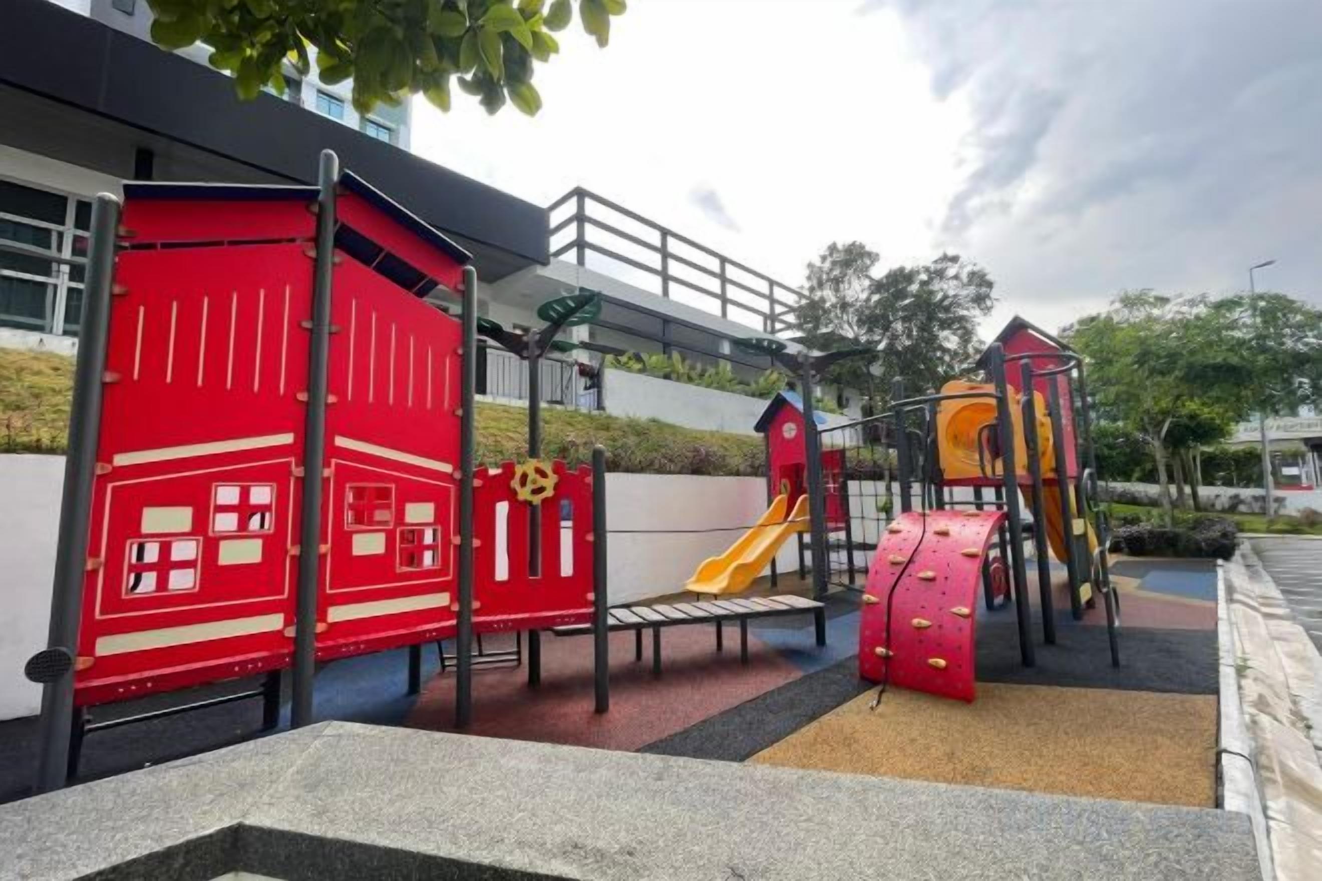 Um parquinho com diversas estruturas de recreação, incluindo uma parede de escalada vermelha, um escorrega e um tobogã vermelho.