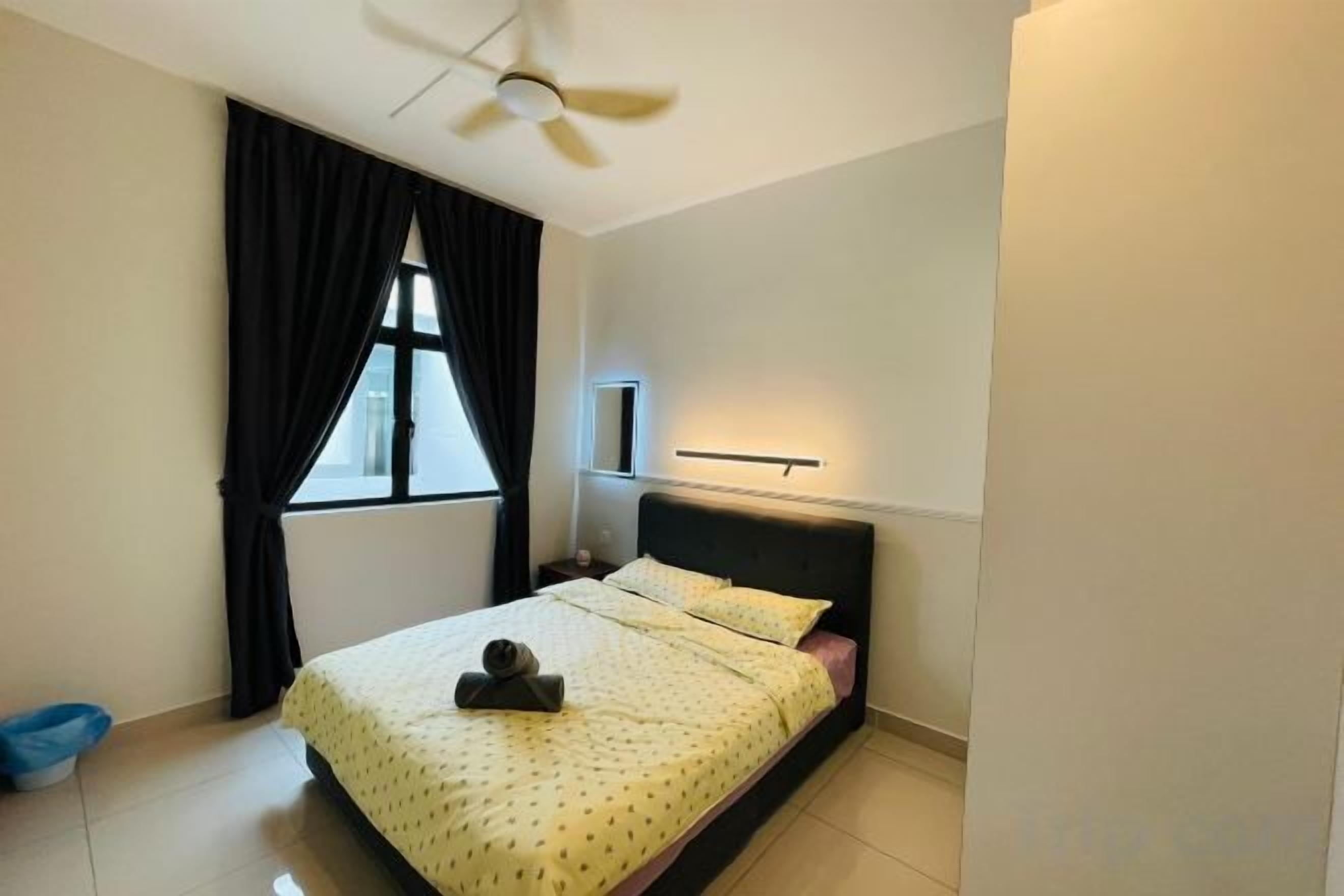 Quarto com cama, ventilador de teto, janela com cortinas e mesa de cabeceira.