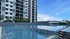 A modern building with a swimming pool, featuring a patterned tile design and a clear blue sky. - Desaru Utama A14 by UcomeHomestay (Bandar Penawar)