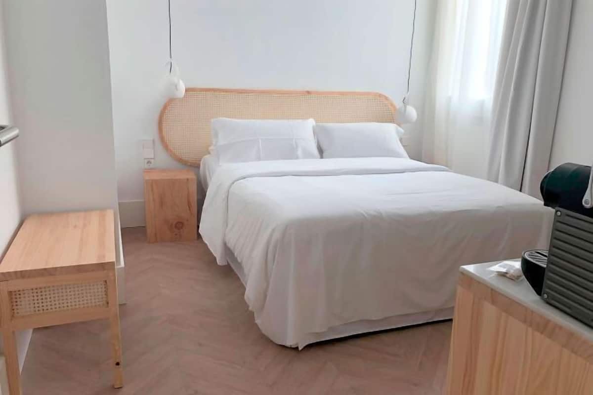 A neatly arranged hotel room with a bed, bedside table, and a small wooden nightstand.