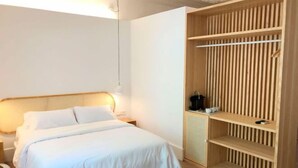 Une chambre à coucher comprenant un lit, une table de chevet et une armoire en bois avec des étagères.