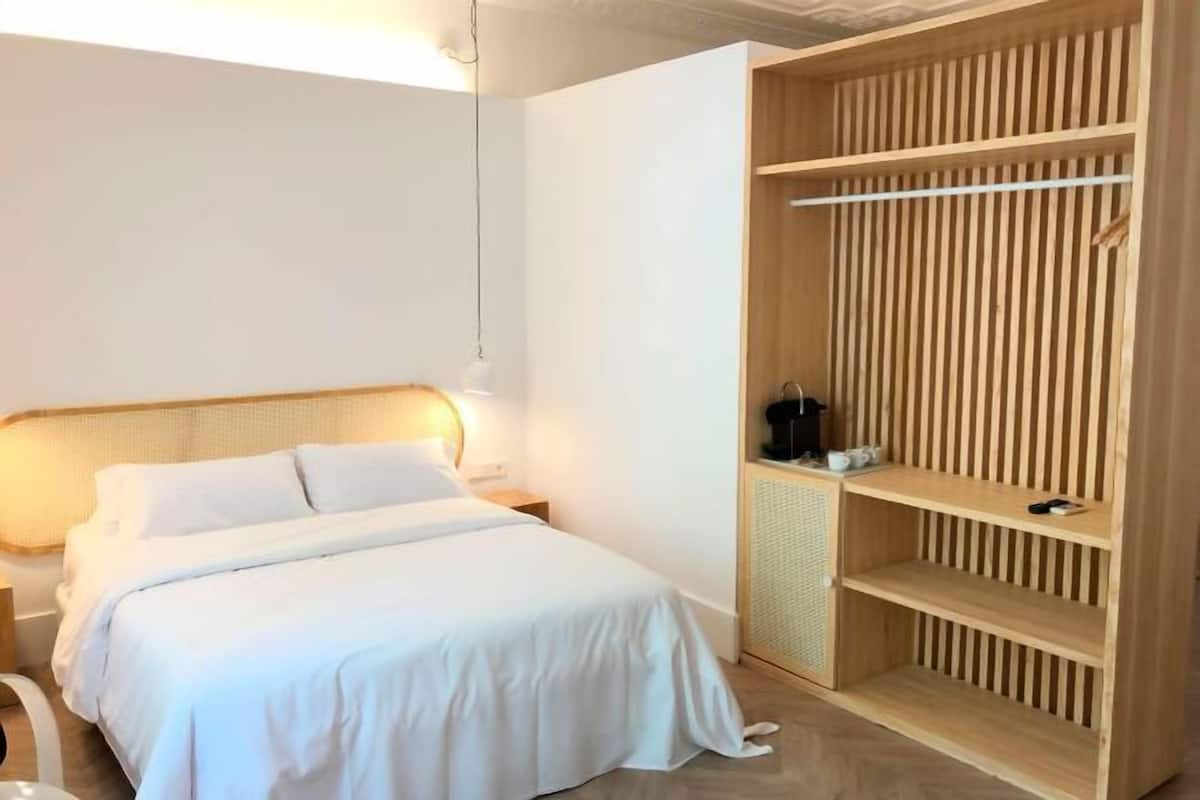 A bedroom with a bed, bedside table, and a wooden wardrobe with shelves.
