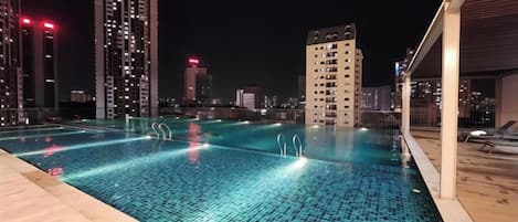 Una piscina en la azotea con vistas a un paisaje urbano, rodeada de edificios altos.