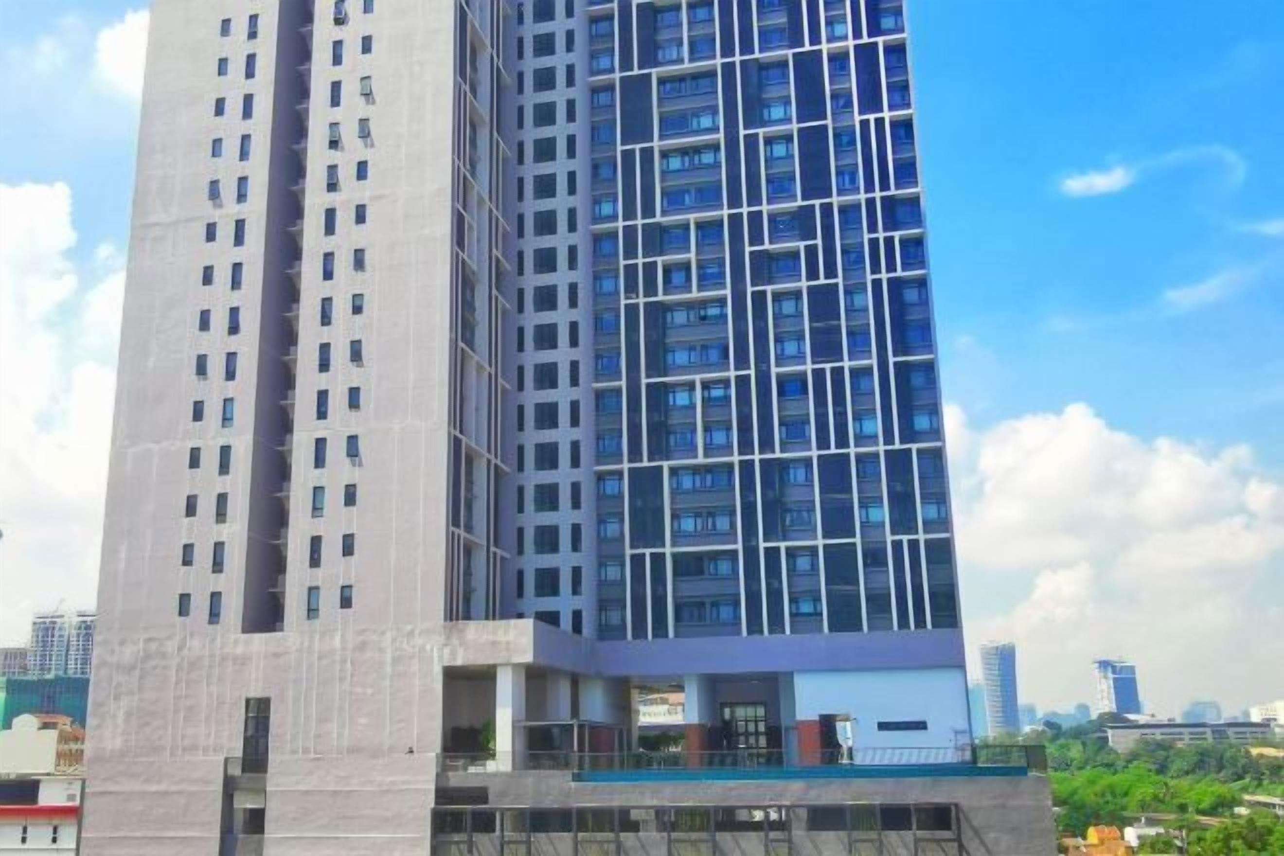 Um edifício alto com design arquitetônico moderno, apresentando uma grade de janelas e uma área de entrada destacada.