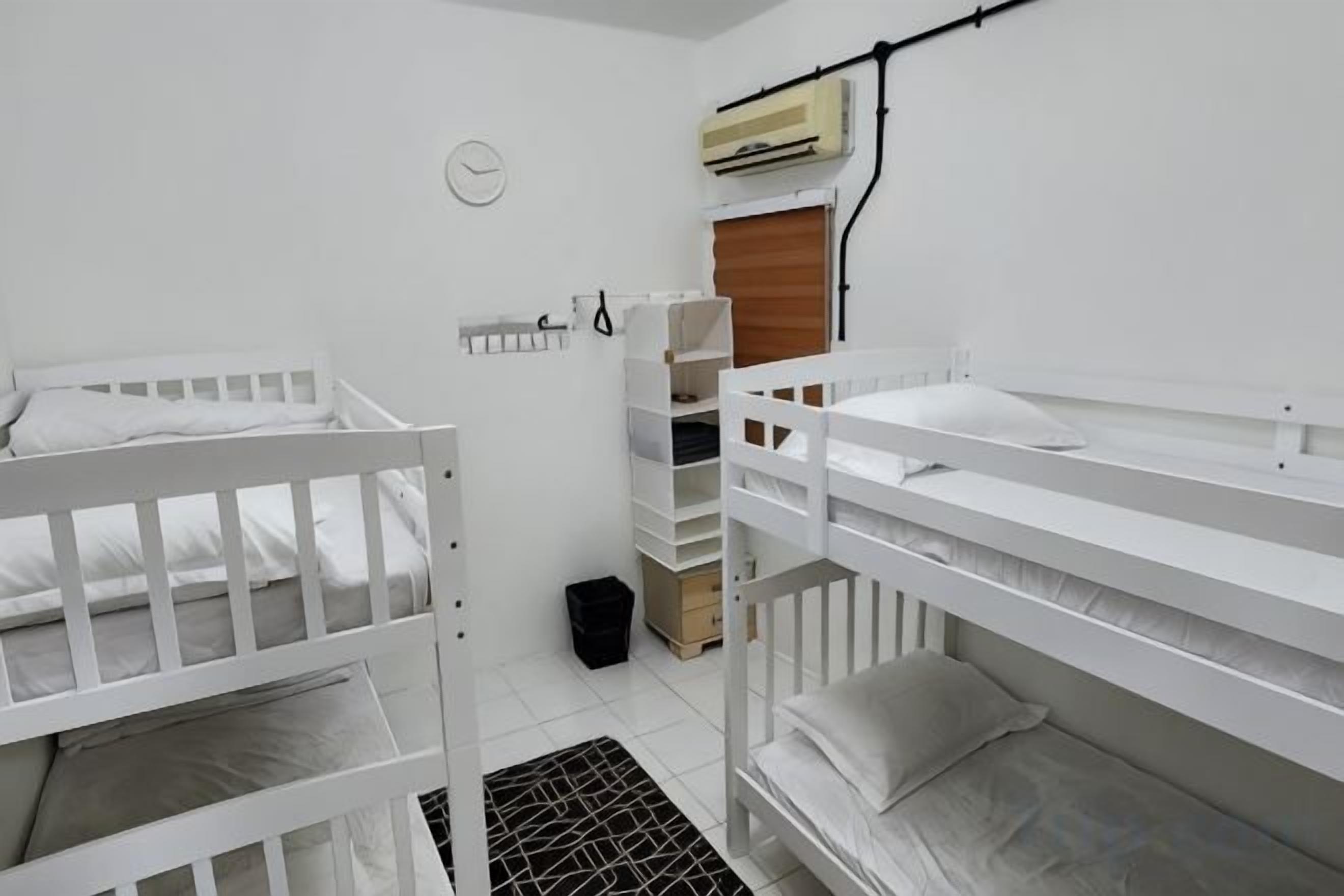 Quarto com beliches, uma pequena janela e ar condicionado fixado na parede.