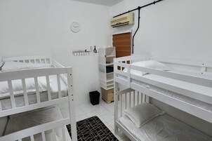 Una habitación con literas, un ventanal pequeño y un aire acondicionado de pared.