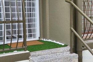 Una escalera con barandilla metálica que conduce a una puerta con ventanal.