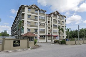 A multi-story hotel with a central entrance, a signboard, and a parking area.
