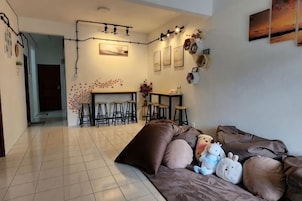 Una sala de estar con un sofá, una mesa de centro y un área de cocina con taburetes.