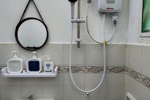 A bathroom with a shower, a toilet, and a sink. There are three bottles on a shelf.