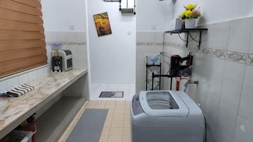 Une petite salle de bain comprenant des toilettes, un lavabo et une petite étagère où sont rangés les articles de toilette.