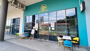 The exterior of Artsy Café with large windows, outdoor seating, and a teal-colored wall. - JQ Unity Homestay Seaview 6pax (Kota Kinabalu)