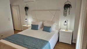 Una camera da letto con un letto, comodini e piante pensili.