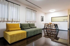 A modern living room with a sofa, a dining table, and a kitchen area. - 10 Min Walk to Ikebukuro Station 4BR Private House 3 Min to Kanamecho Sleeps 8 (Tokyo)
