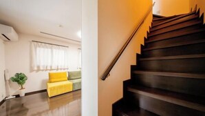 A modern living room with a wooden staircase. - 10 Min Walk to Ikebukuro Station 4BR Private House 3 Min to Kanamecho Sleeps 8 (Tokyo)