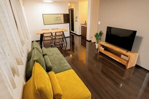 A modern living room with a sectional sofa, a flat-screen TV, and a dining area with chairs and a table. - 10 Min Walk to Ikebukuro Station 4BR Private House 3 Min to Kanamecho Sleeps 8 (Tokyo)